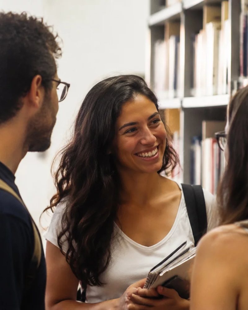 Pessoas conversando de pé entre as prateleiras de uma biblioteca