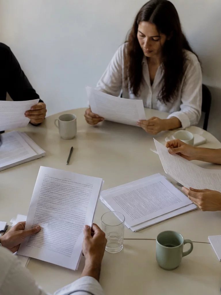 Sala de reunião clara, uma pessoa em pé explicando um ponto ao grupo